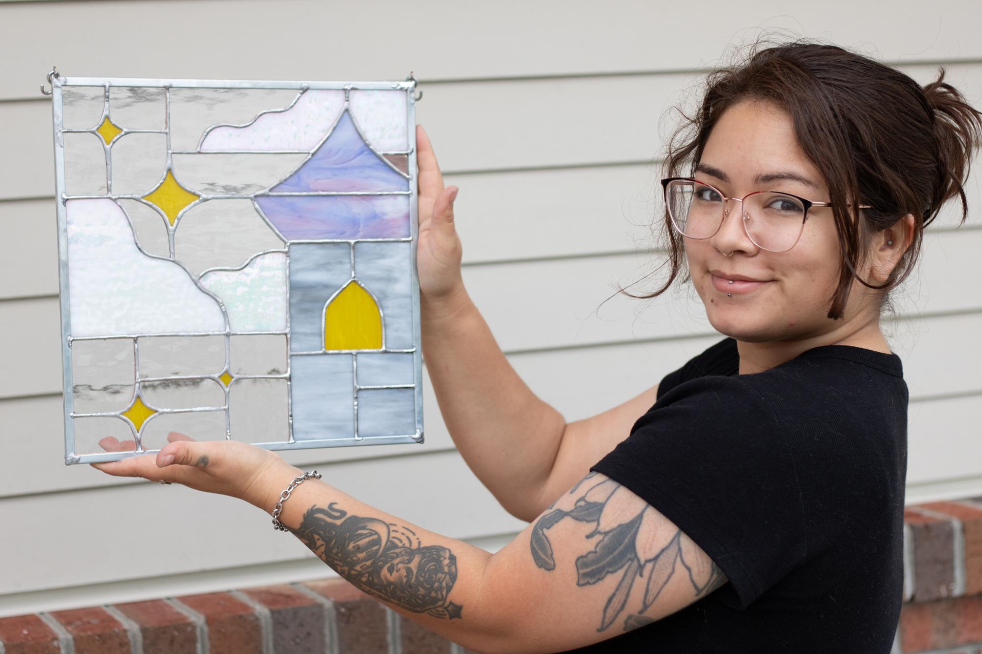 Young woman holding her completed stained glass piece