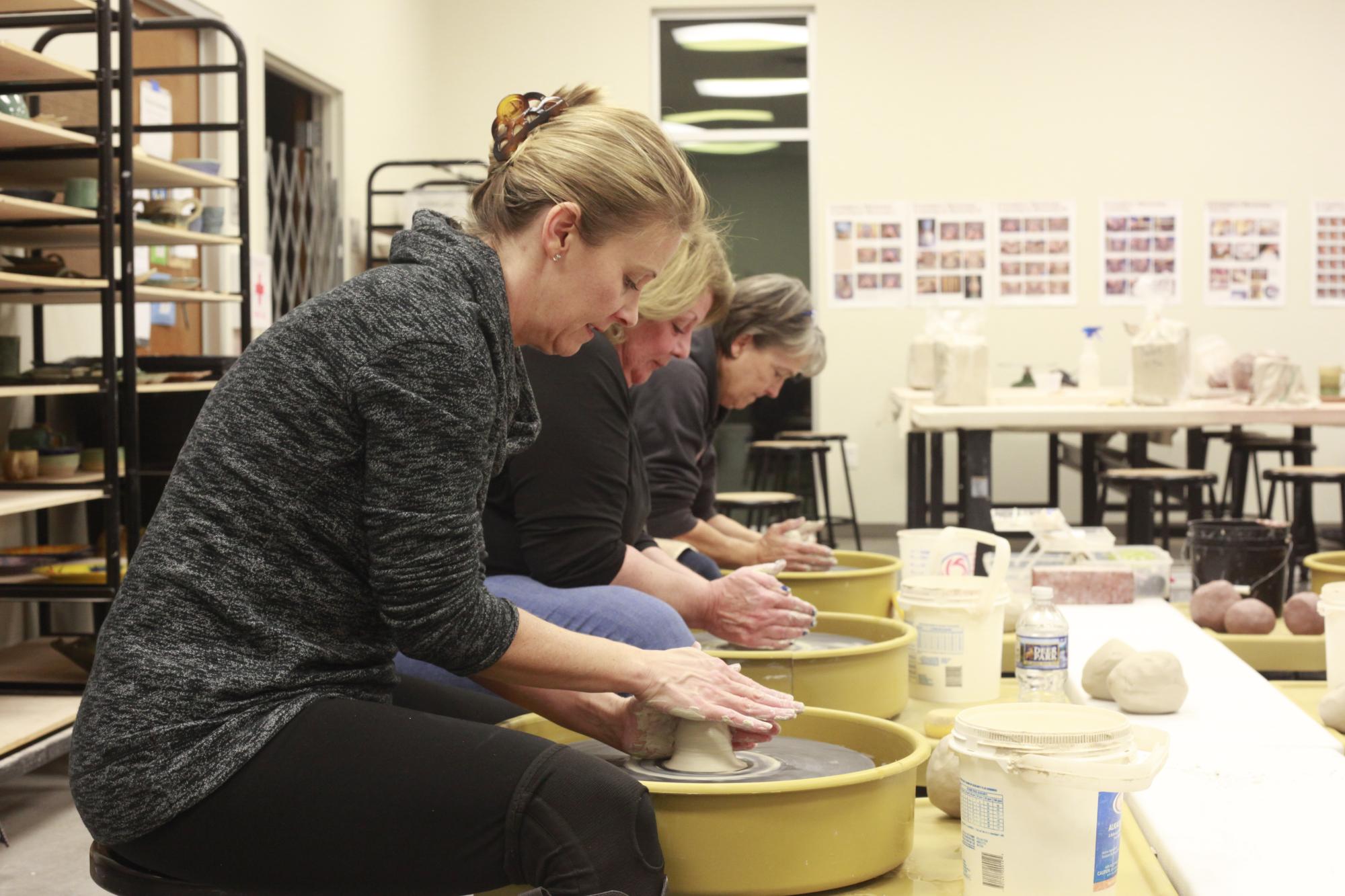 Women throwing on pottery wheels 