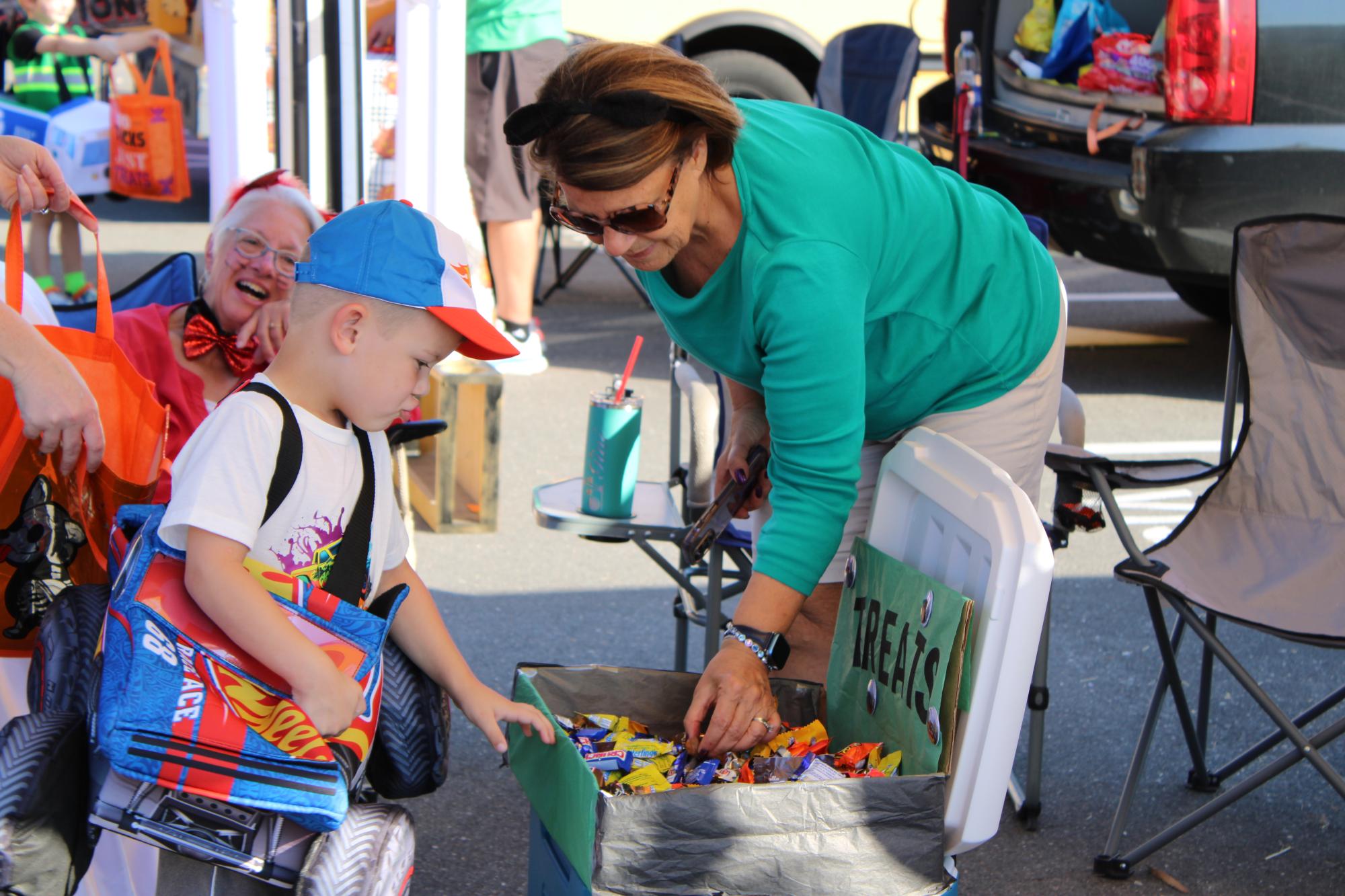 Young child dressed in a costume picking out candy from booth