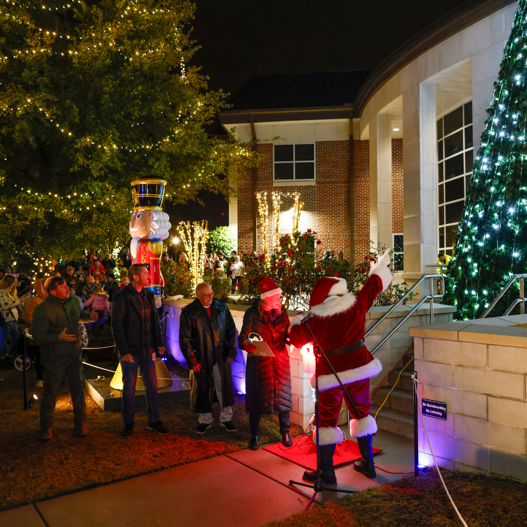 Santa pointing at a tree with crowd